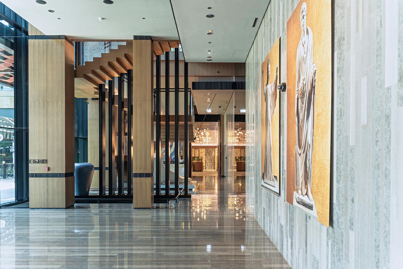 Elegante Hotellobby mit Marmorboden, modernem Holzdesign und Tageslicht durch Glasfront.