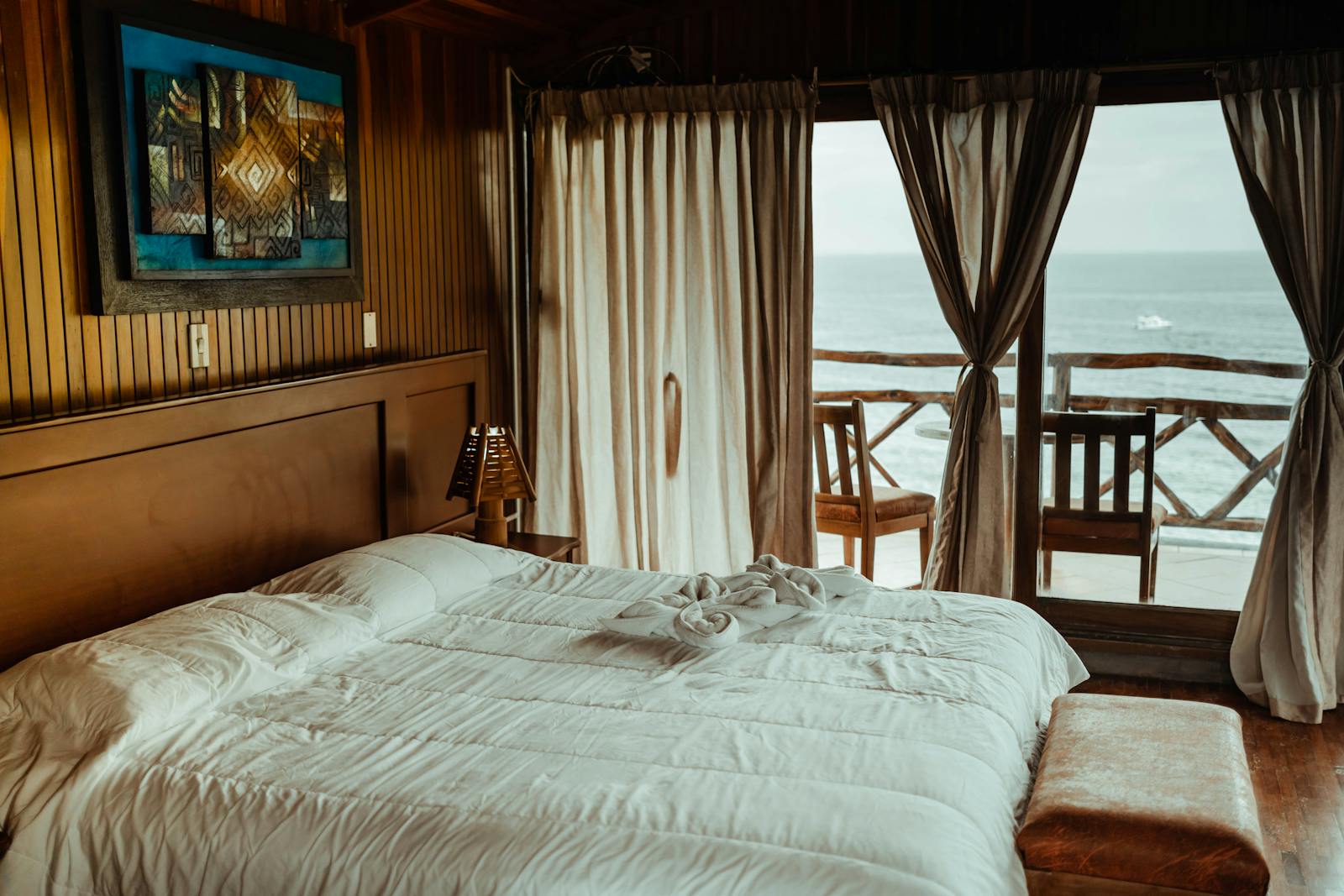 Stilvolles Hotelzimmer mit Doppelbett, gepflegter Bettwäsche und Meerblick durch offene Vorhänge.