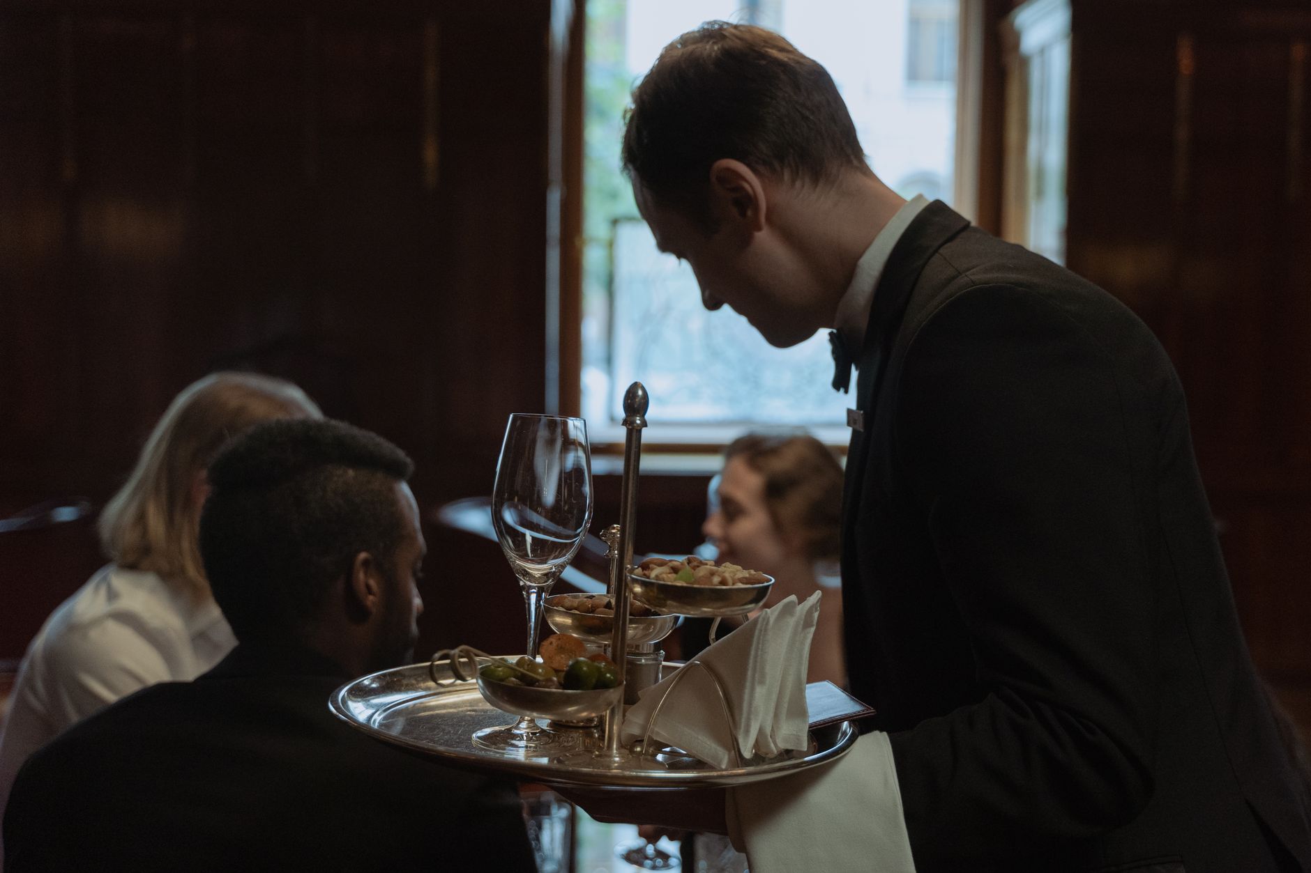 Kellner serviert einer Gruppe von Gästen an einem gedeckten Restauranttisch.