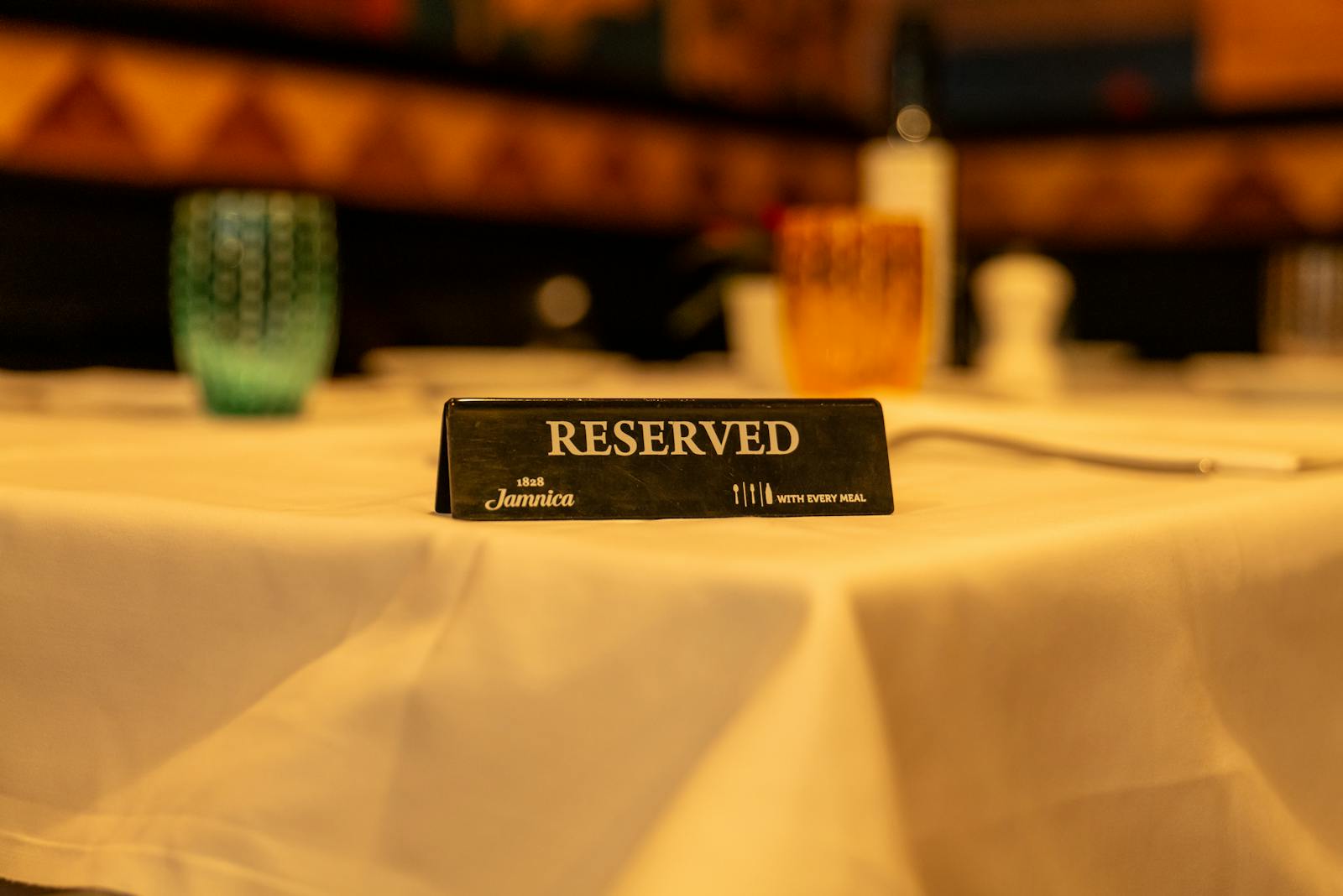 Reserviert-Schild auf einem weiß gedeckten Restauranttisch bei warmem Licht.